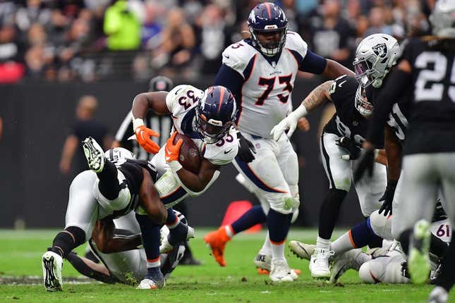 Oct 2, 2022; Paradise, Nevada, USA; Denver Broncos running back Javonte Williams (33) is brought down by Las Vegas Raiders linebacker Denzel Perryman (52) during the first half at Allegiant Stadium.
