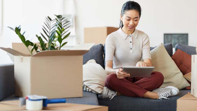 Woman using digital tablet while packing boxes 