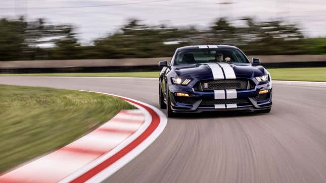 A photo of a blue Ford Mustang GT350 driving round a race track. 