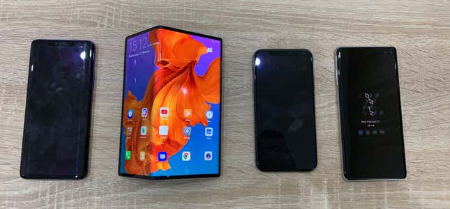 The Mate X next to a Huawei P20 (far left), an iPhone XS (second from right), and the Samsung Galaxy S10+ (far right).