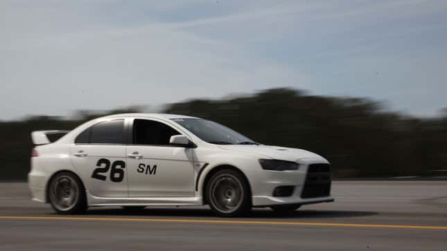 A photo of a white car driving in Autocross. 