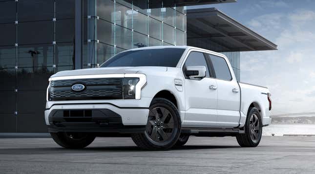 A bright white 2023 Ford F-150 Lightning is parked in front of a glass building.