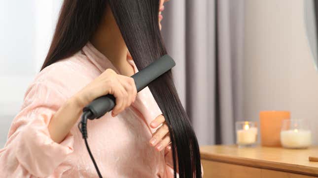 woman straightening her hair with a flatiron