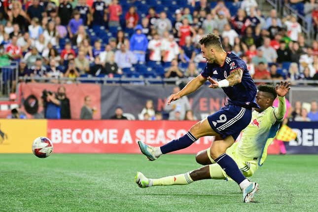 Aug 30, 2023; Foxborough, Massachusetts, USA; New England Revolution attacker Giacomo Vrioni (9) scores a goal as New York Red Bulls defender Hassan Ndam (98) slides to defend the shot during the first half at Gillette Stadium.