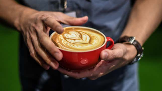 Man holds elaborate latte in mug