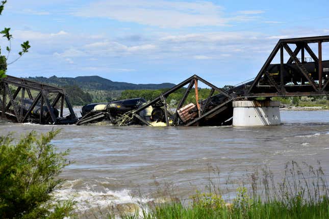 Several train cars are immersed in the Yellowstone River after a bridge collapse near Columbus, Montana, on Saturday, June 24, 2023.