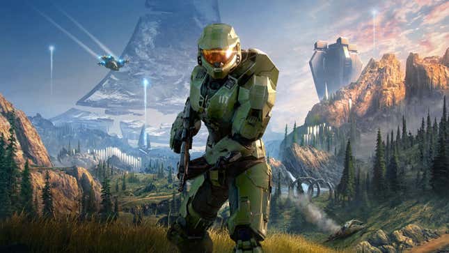 Master Chief stands in front of a mountain region while a ship flies behind him.