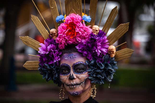 A woman wears a crown of colorful flowers and skulls. 