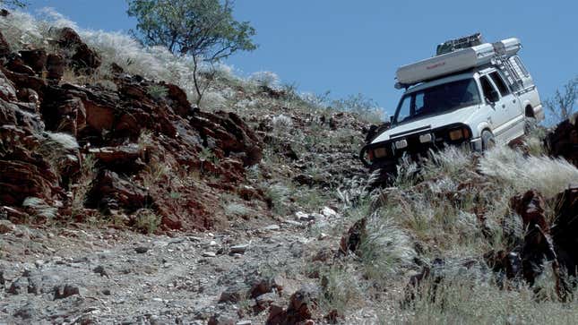A photo of a white truck on a rocky off-road trail. 