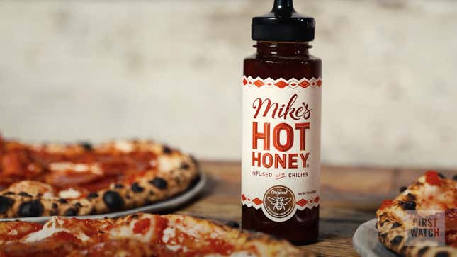 Mike's Hot Honey bottle beside trays of pizza