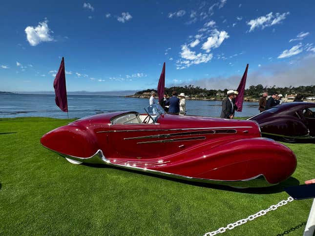 A red 1939 Delahaye Type 165 Cabriolet is parked on the green at Pebble Beach