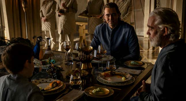 Three of Foundation's Empires sit around a rectangular table to eat a lavish meal. Left to right: Cooper Carter's Young Brother Dawn, Lee Pace's Brother Day, and Terrence Mann's Brother Dusk.