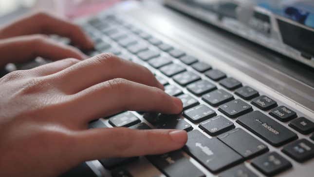 a person's hands typing on a laptop