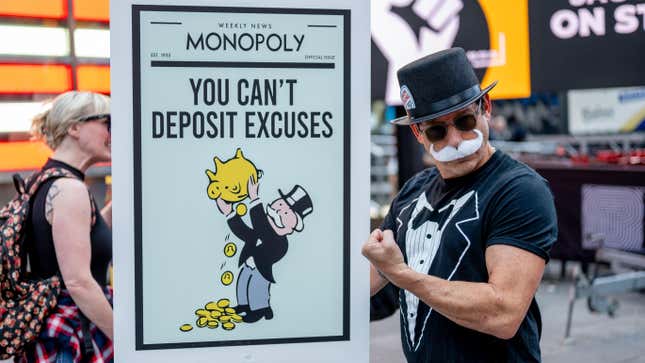 A man dressed as the Monopoly man holds a Monopoly-themed protest sign on the picket line