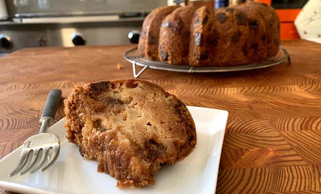 Slice of Apple Cake With Chocolate Chunks in foreground, with full cake in background