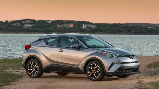 A photo of a silver Toyota C-HR crossover parked by a lake. 
