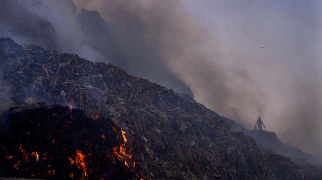A man walks through the Bhalswa landfill as the fire rages.