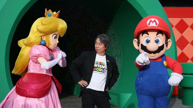Shigeru Miyamoto poses next to Princess Peach and Mario. 