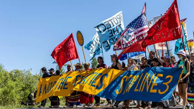Climate activists and Indigenous community members hold a banner and flags during a rally and march in Solway, Minnesota on June 7, 2021. 