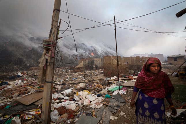 A woman stands near the edge of the landfill.