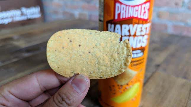 hand holding Pringles Harvest Blends Farmhouse Cheddar chip