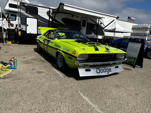 A lime green Dodge Challenger Trans-Am car is parked in the pits at Laguna Seca