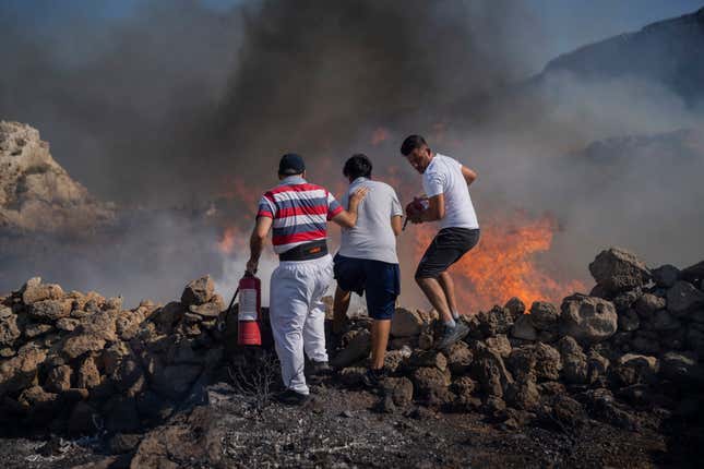 Local residents try to extinguish a fire, near the seaside resort of Lindos, on the Aegean Sea island of Rhodes, southeastern Greece, on July 24, 2023.