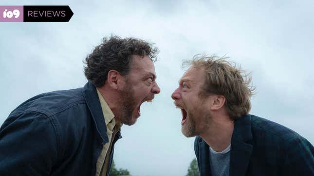 Two men in blue jackets scream theatrically into each others' faces, mouths and eyes open wide.