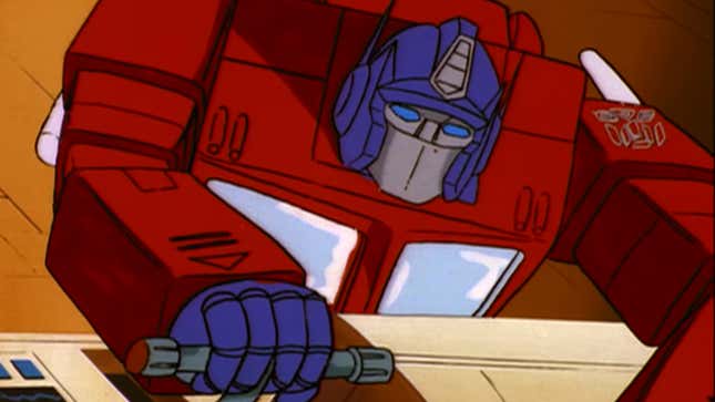 A hunched-over Optimus Prime frantically tries to work his spaceship's controls.