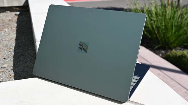 A Microsoft Surface Laptop Go 2 on a white bench surrounded by plants