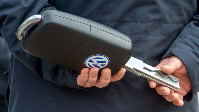 A photo of a man holding an oversized car key in his two hands. 