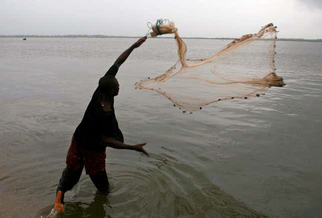 A man casts his fishing net into River Niger in southern Nigeria
