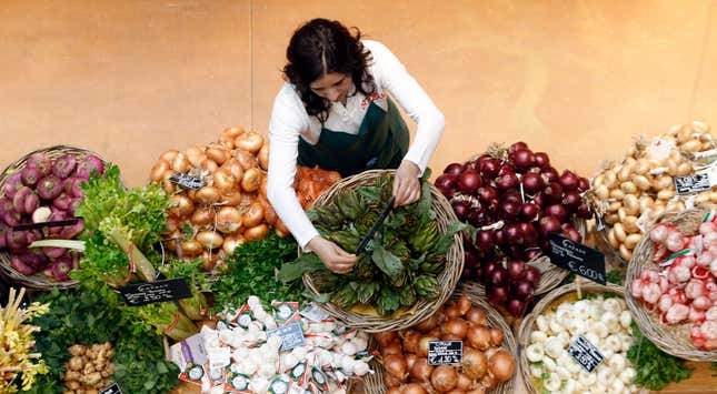 An employee arranges pricetags at a vegetables work bench during the opening day of upmarket Italian food hall chain Eataly's flagship store in downtown Milan