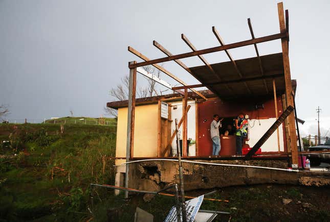 Men gather at a partially destroyed bar three weeks after Hurricane Maria hit the island, on October 11, 2017 in Aibonito, Puerto Rico. 