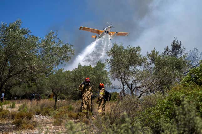 An aircraft drops water as firefighters operate during a wildfire in Vati village, on the Aegean Sea island of Rhodes, southeastern Greece, on July 25, 2023.