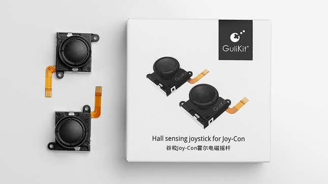 The GuliKit replacement Hall sensing Joy-Con joysticks next to their cardboard packaging.