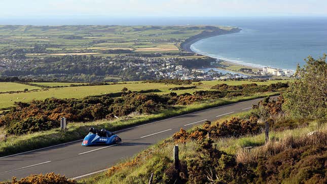 A photo of a motorbike and side car on the Isle of Man TT Course. 