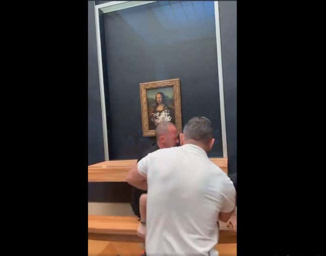 A screenshot of a man being pulled away after throwing a cake at the Mona Lisa is shown.