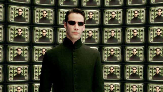 Neo standing before multiple television screens on which he is standing in front of multiple television screens.