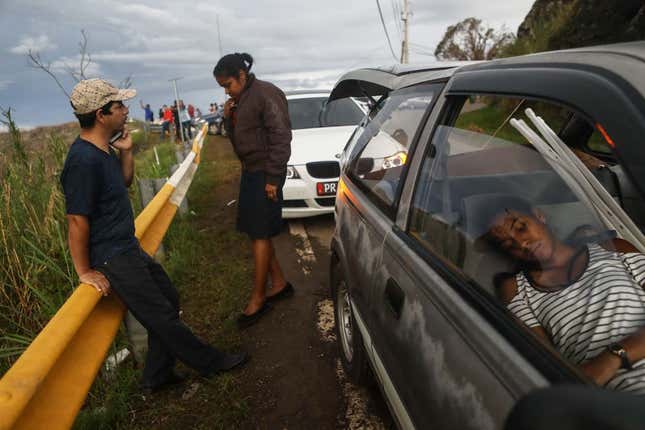  Family members gather while attempting to speak by phone with another family member along a roadside near the top of a mountain, more than two weeks after Hurricane Maria swept through the island, on October 6, 2017 in Orocovis, Puerto Rico.