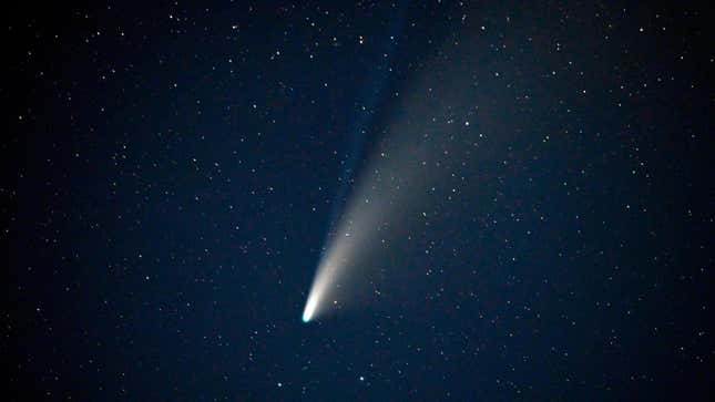 A bright yellow-white streak at center is the comet NEOWISE, against the deep blue night sky.