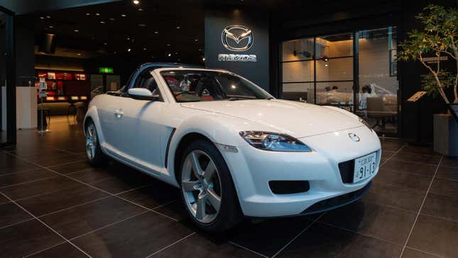An image of a white, roof-less Mazda RX-8 in one of the brand's showrooms.