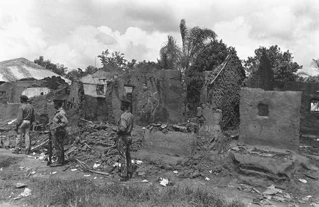 Nigerian federal troops wait to move their position, surrounded by gutted buildings at Ngu, about 10 miles from Umuahia, 1969.