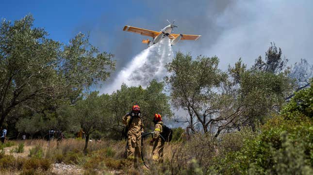 An aircraft drops water as firefighters operate during a wildfire in Vati village, on the Aegean Sea island of Rhodes, southeastern Greece, on July 25, 2023.