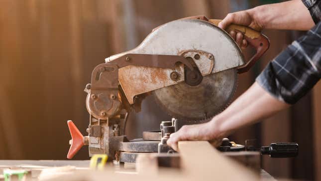 A man is seen using a circular cutting saw to cut wood