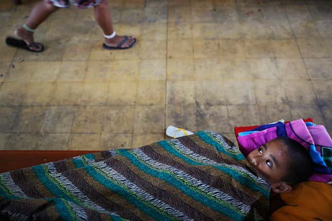 An ill child looks from under the blanket as another boy walks by in a church where hundreds of survivors of Typhoon Haiyan found shelter in Tacloban November 21, 2013. As millions of dollars pour in for more than four million left homeless by a typhoon in the central Philippines, authorities are grappling with a familiar problem - how to stop fraudulent claims and prevent greedy politicians taking advantage. Typhoon Haiyan smashed through the country on November 8, laying waste to just about everything in its path, and killing more than 4,000 people.