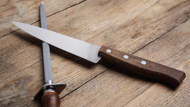 A knife and honing steel sit on a table.