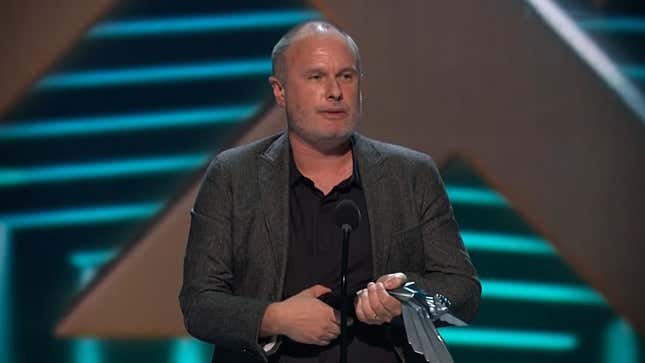 A screenshot shows Unsworth holding a trophy on stage at the 2018 Game Awards. 