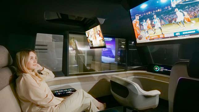 A person sitting in the back seat of LG Display's autonomous concept car watching basketball being played on a retractable OLED display extending from the ceiling.