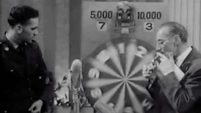 A You Bet Your Life contestant watches the spinning wheel while host Groucho Marx does not.